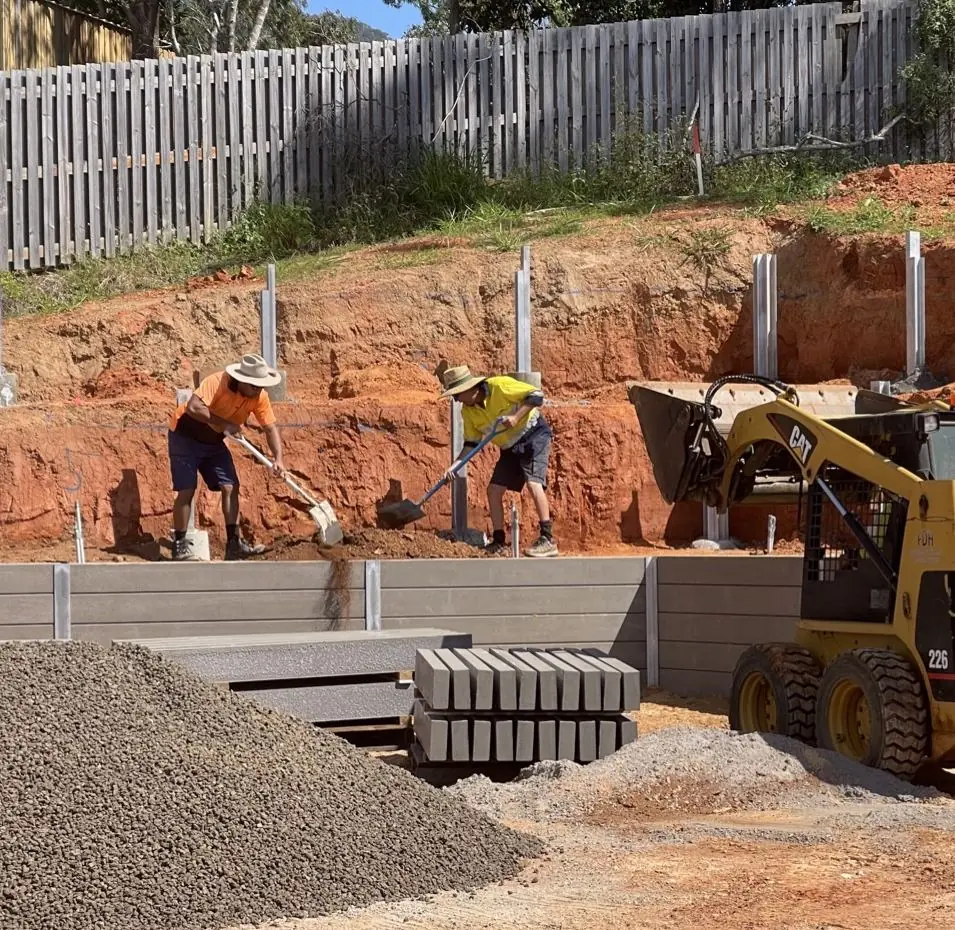 Crew backfilling a concrete sleeper wall