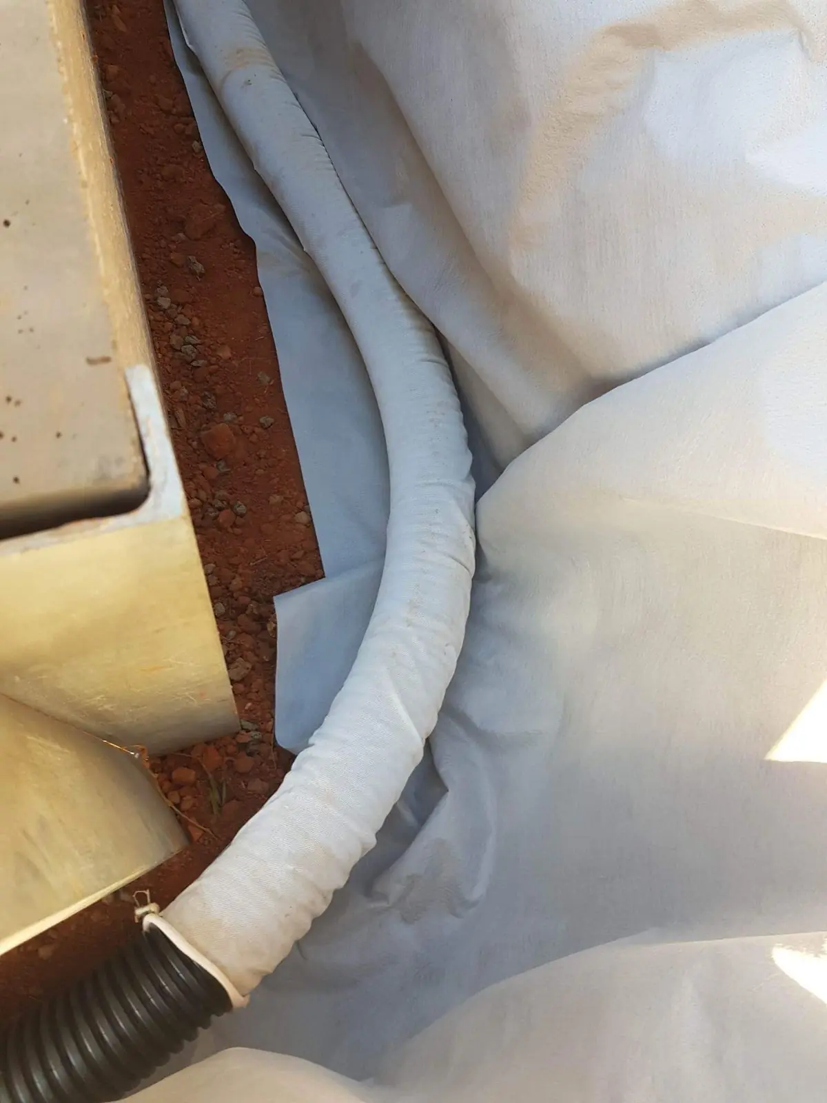 Socked ag pipe laid on geofabric behind a retaining wall, joined to the outlet