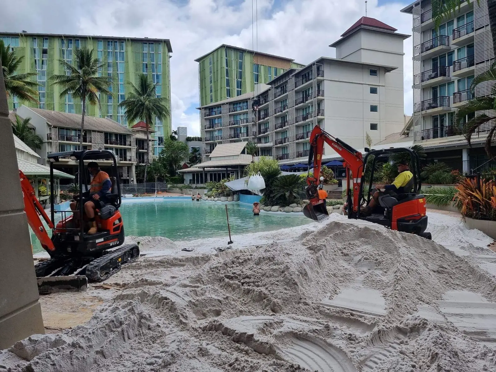 Two mini excavators working on a resort lagoon pool