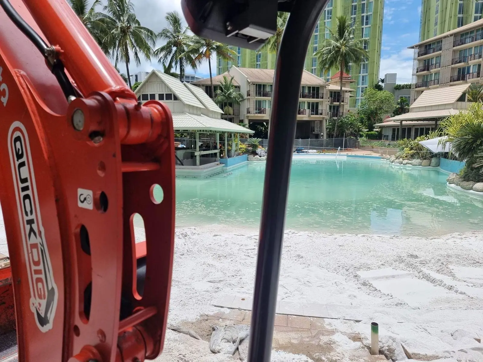 QuickDig excavator arm beside a Cairns resort lagoon pool