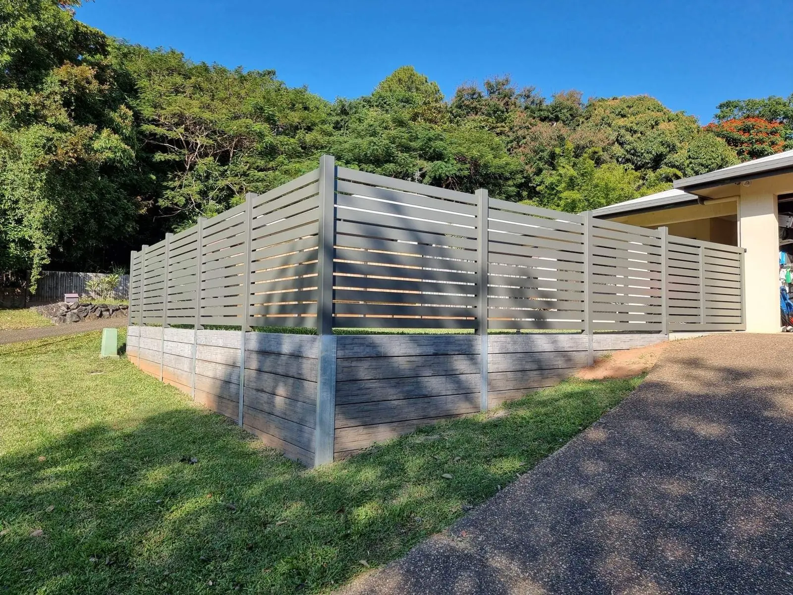 Aluminium slat fence on stone-look concrete sleeper retaining wall